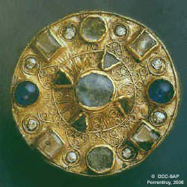 Fibule du 7e s. ap. J.-C. faite d’une feuille d’or sertie avec des clous en argent sur un disque en bronze et ornée de fausses pierres en verre teinté. Diamètre: 4 cm.
