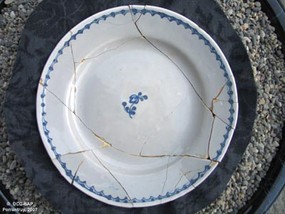 Assiette plate en faïence blanche à motif de rameau bleu central.