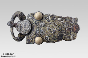 Plaque-boucle finement damasquinée découverte dans une tombe.