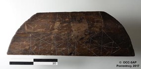 Le fragment de couvercle d'un tonneau en bois, reconverti en plateau de jeux d'Alquerque.